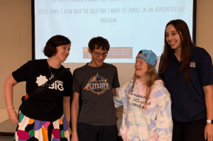 Dream Big staff and students laughing together in front of a student's presentation on the final day of Camp.