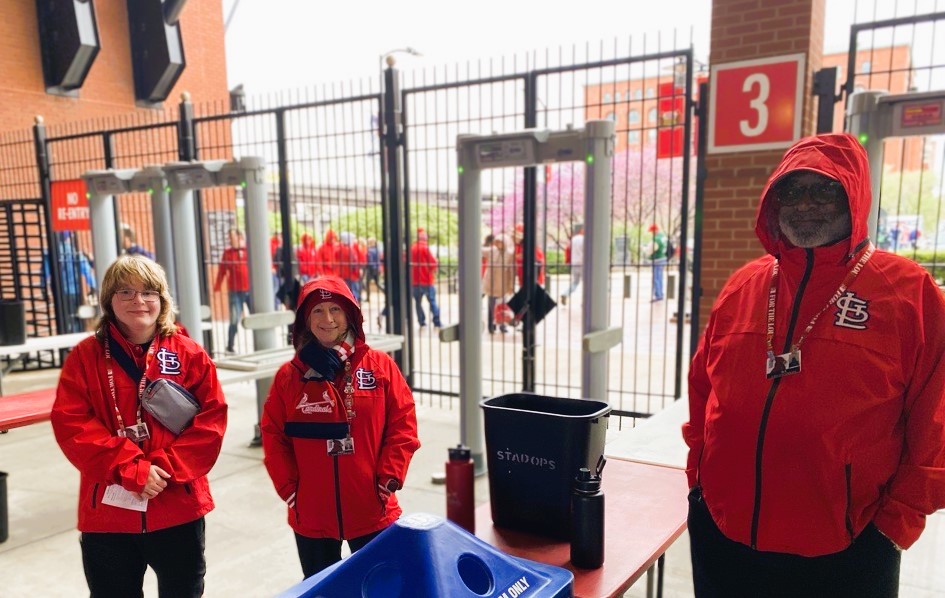 Three staff members in Cardinals gear working an admission gate at Busch Stadium
