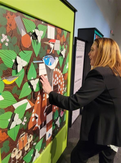 1 – Lori at the Pittsburgh Children’s Museum Starkloff Disability Institute Executive Director Lori Becker interacting with a bright green forest display from "i am wild: a charley harper exhibit."