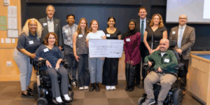 A group of WashU students and SDI leadership and staff smiling during the check presentation.