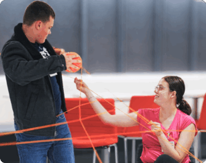 Students playing a group game with a large ball of yarn crisscrossed between them.