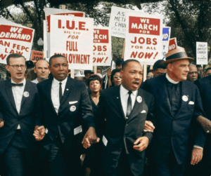 MLK leading a march with signs about right to jobs.