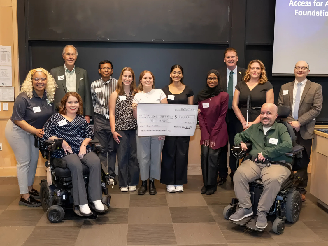 A group of WashU students and SDI leadership and staff smiling during the check presentation.