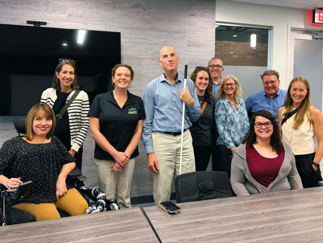 Chris Downey with local architects and SDI staff smile together in a conference room.