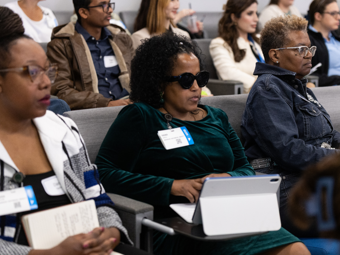 A member of a conference audience uses assistive technology to take notes.