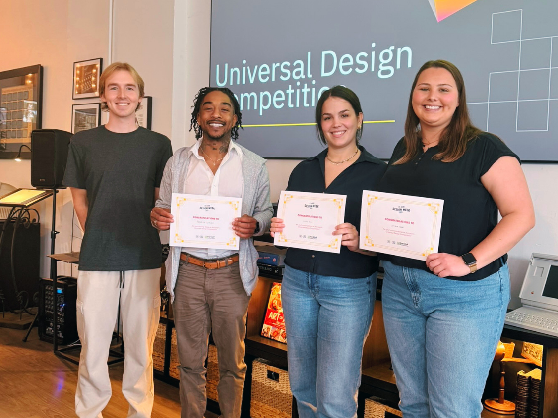 Four college students smiling at the UD competition. Three are holding first place certificates.