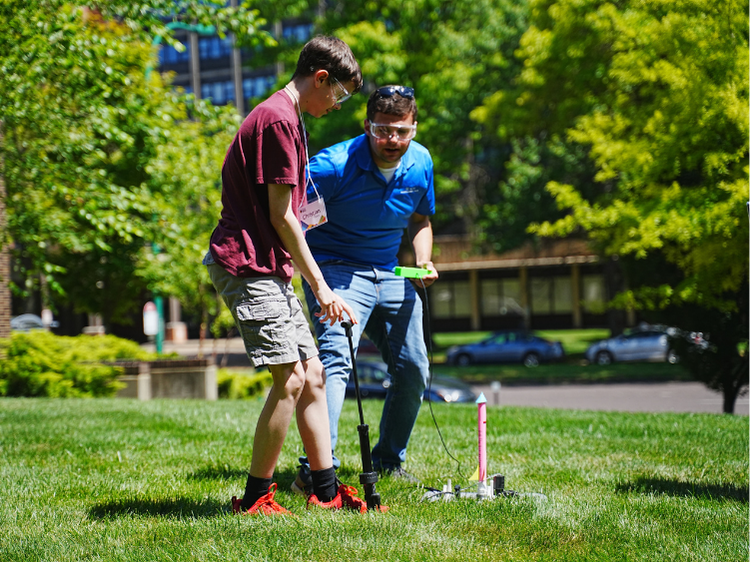 Student and adult preparing a model rocket for launch.