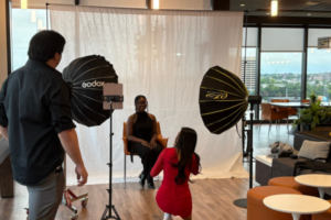 A professional photographer takes a portrait of a young professional.