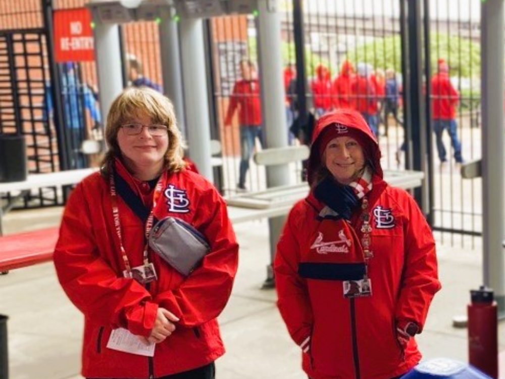 Two Cardinals employees smiling at a Busch Stadium entrance gate.