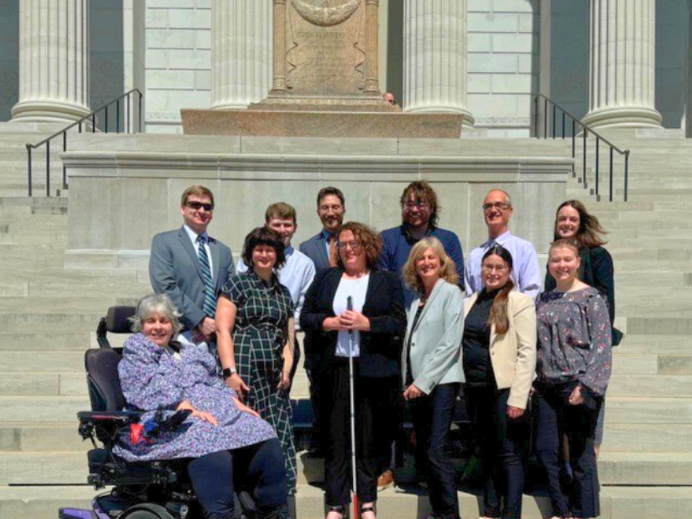 12 professionals smiling on the steps of Missouri's capitol building, some of whom have obvious disabilities. 