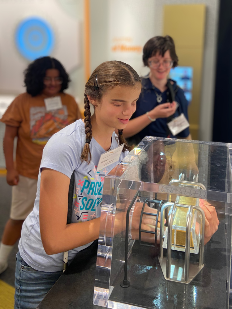 Salome-Dream-Big-Money-Museum Salome testing the weight of a gold bar in a museum.