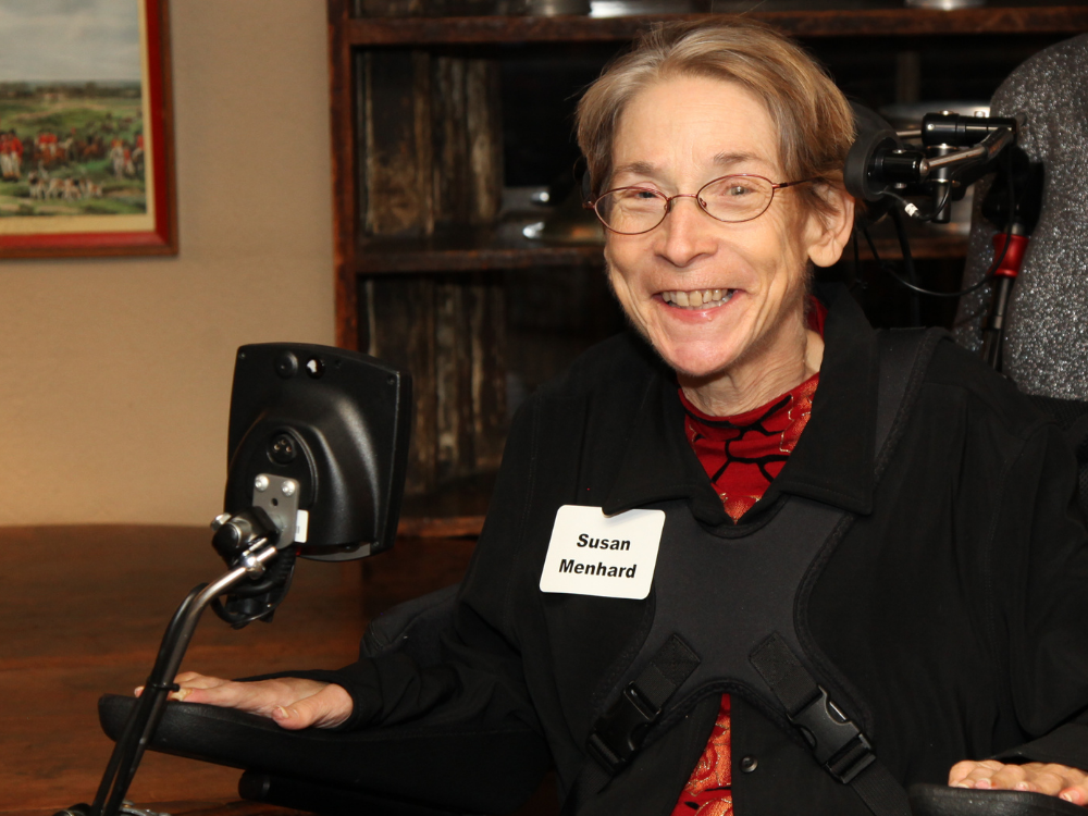 Susan Menhard Susan Menhard with a joyful smile, seated in her power chair that includes head controls.